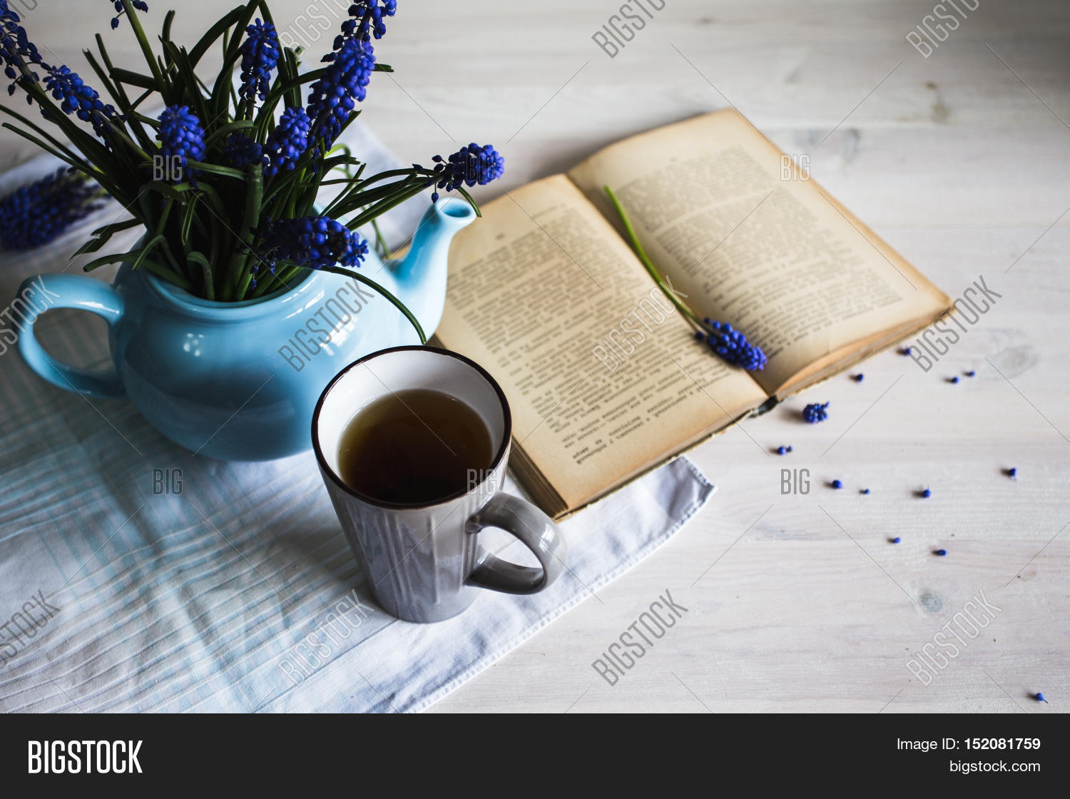 cup of tea with blue flowers and a book on wooden background.