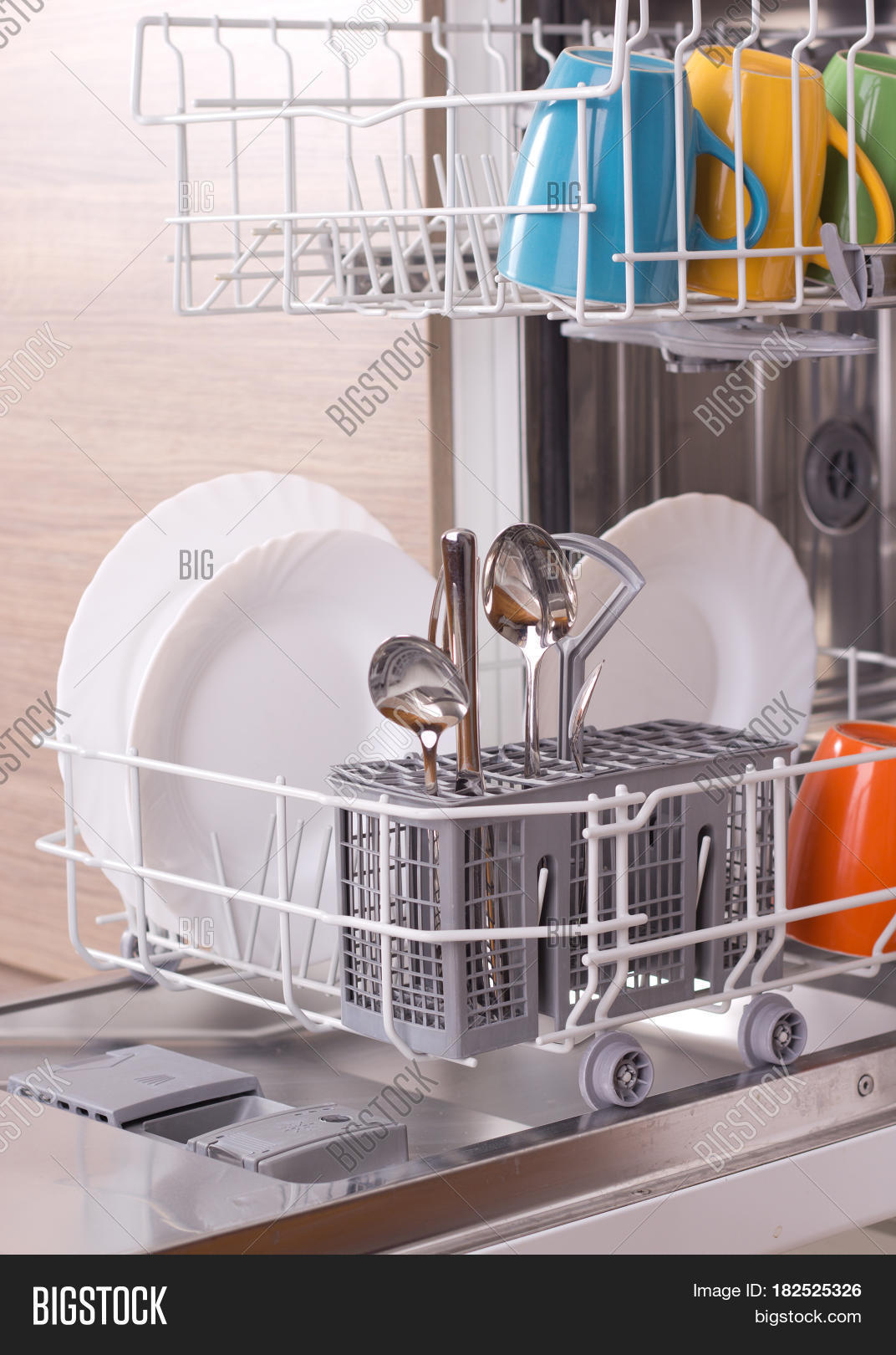 close up of colorful dishware in open dishwasher with kitchen in