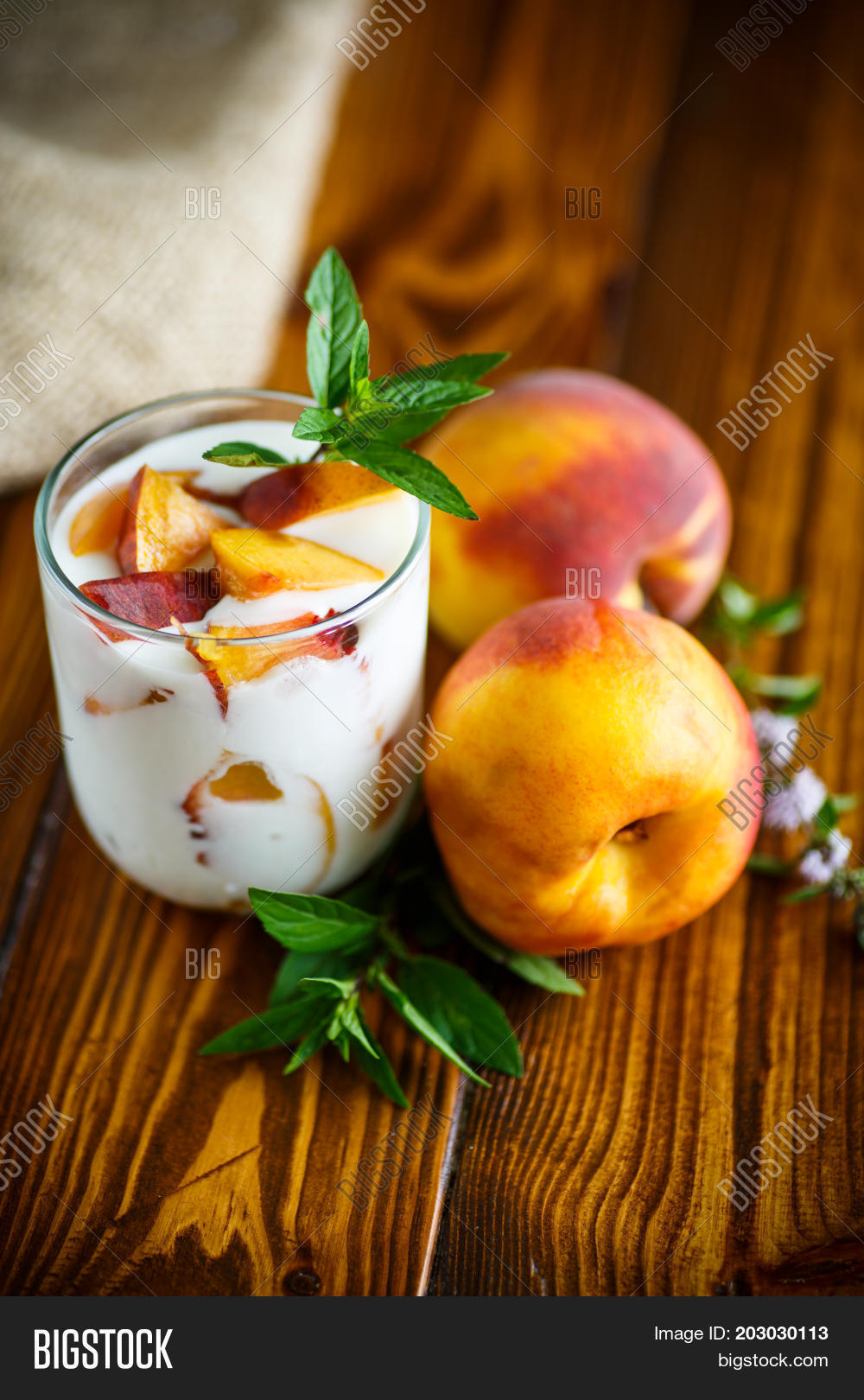 sweet home-made yogurt with pieces of peach in a glass cup