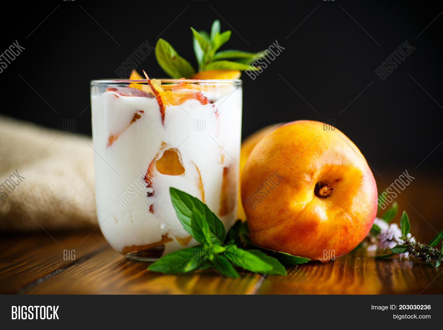 sweet home-made yogurt with pieces of peach in a glass cup