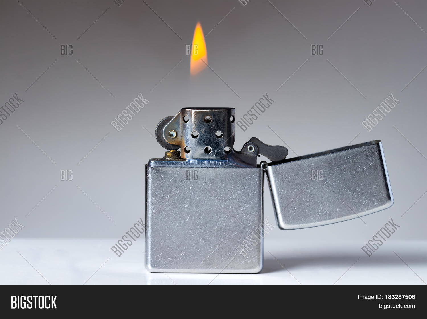 cigarette lighter with flame on white and grey background.