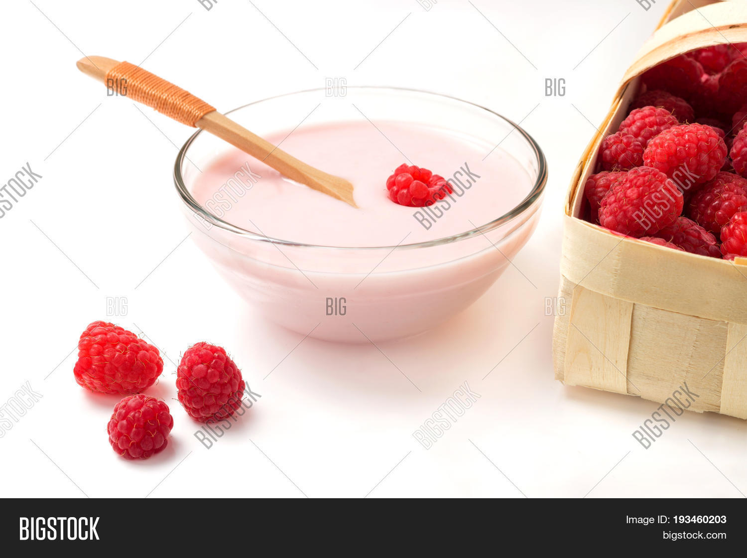 raspberry yogurt in a glass cup with raspberry basket on a white