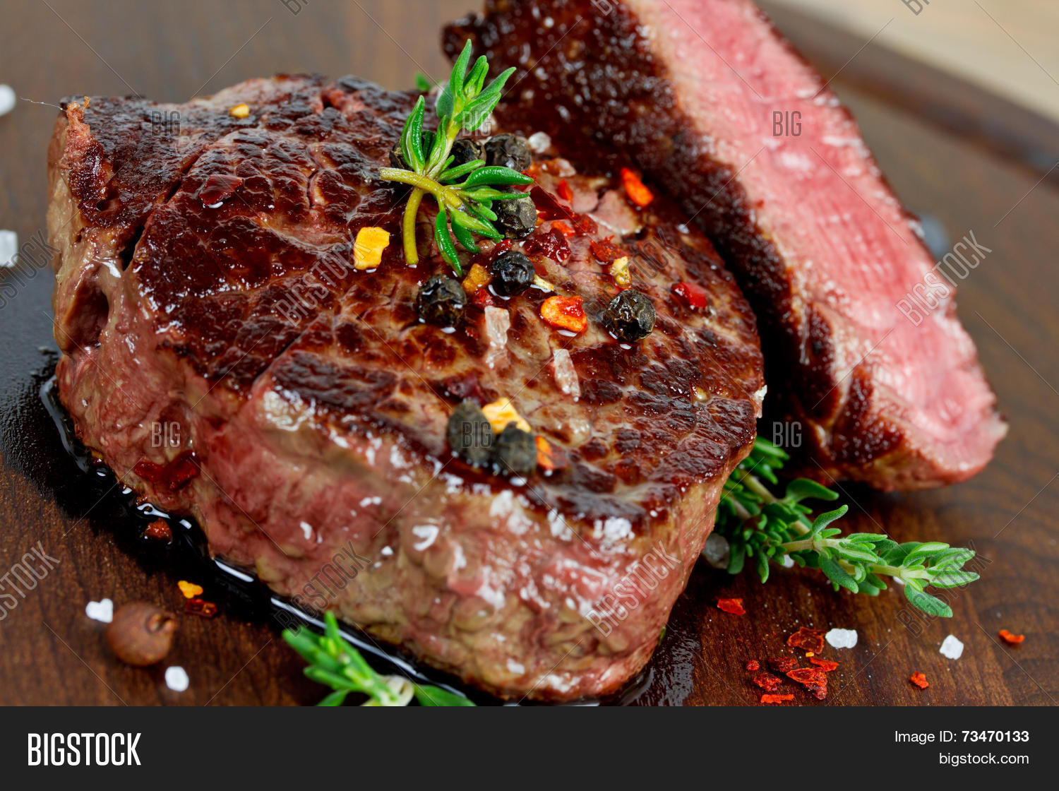 grilled steak with thyme on wooden board