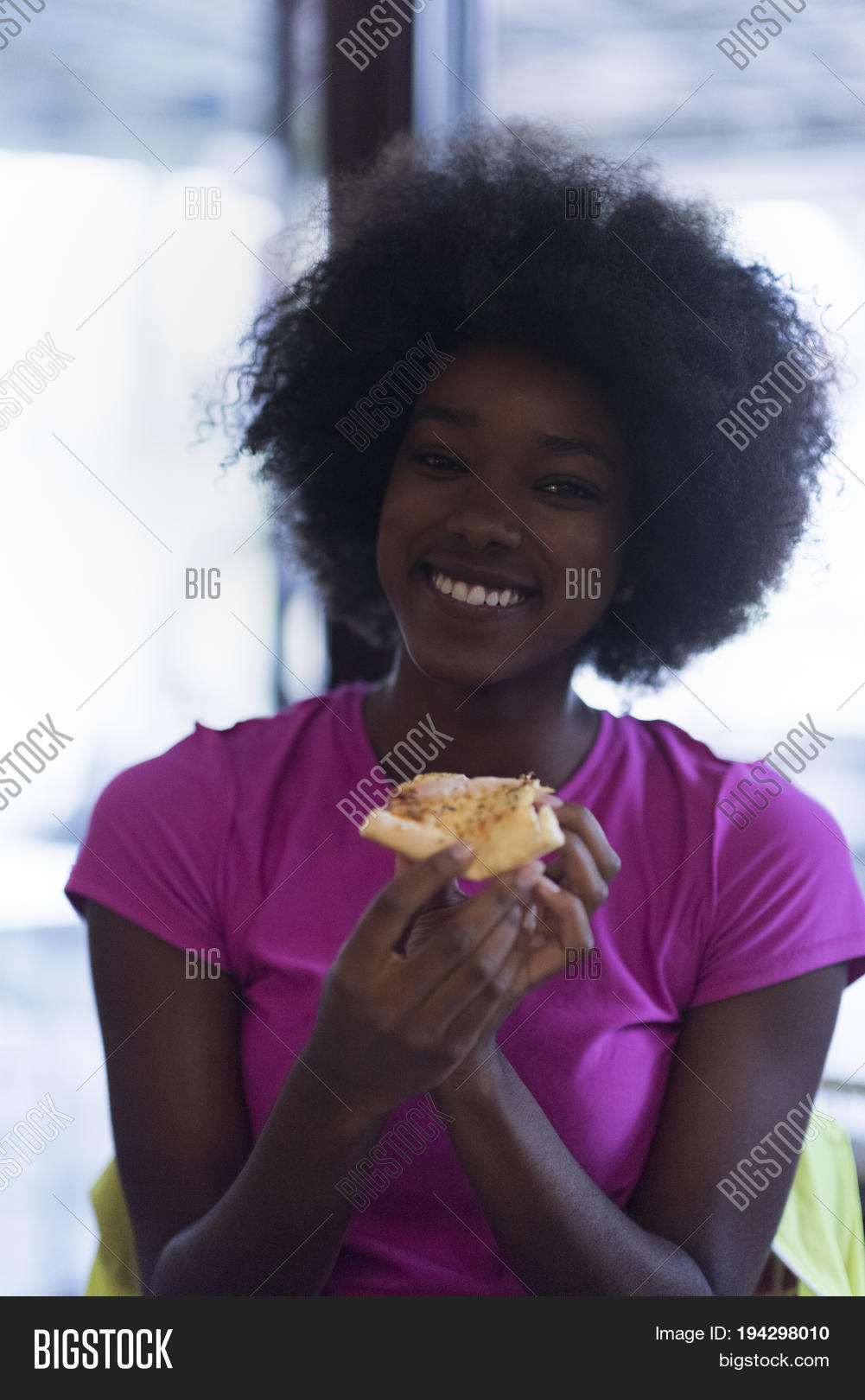 hangry african american woman with afro hairstyle eating tasty