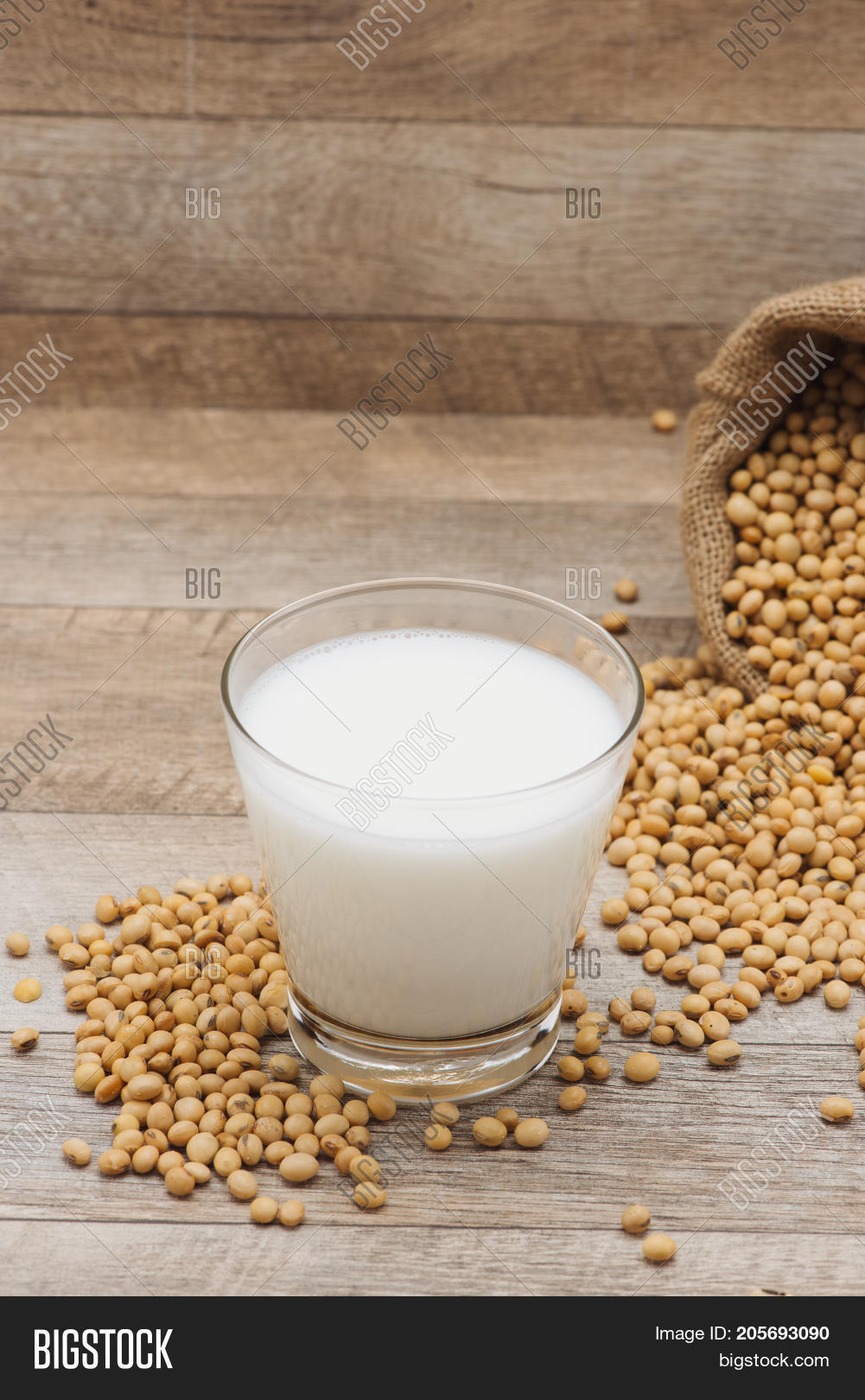 glass with soy milk and soy bean on wooden background