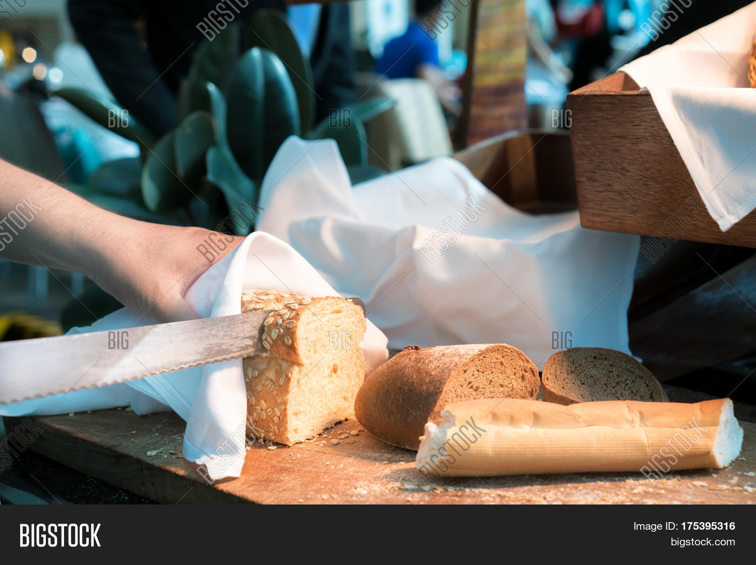 male hands cutting wheaten bread on the wooden board in