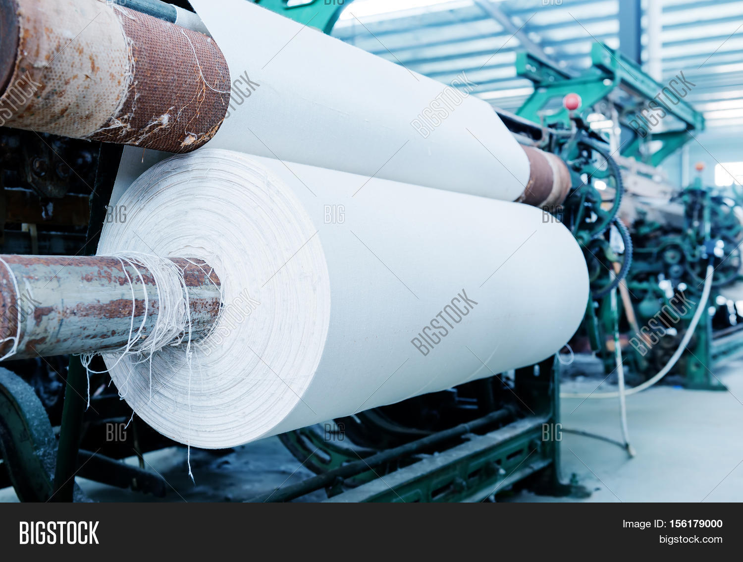 a row of textile looms weaving cotton yarn in a textile mill.