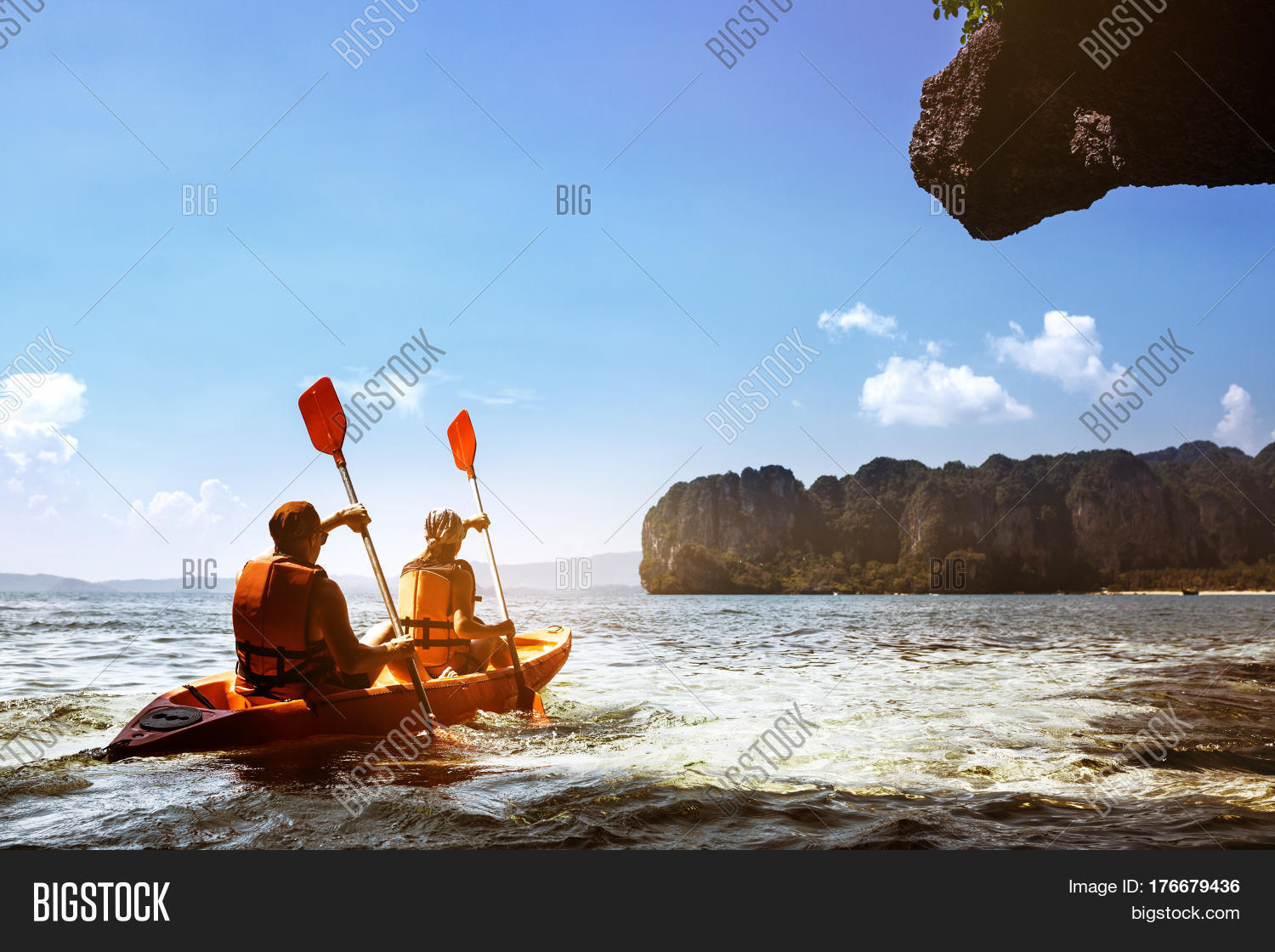 couple canoeing or kayaking at sea island backdrop.