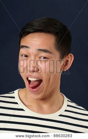 astonished young asian man laughing and looking at camera