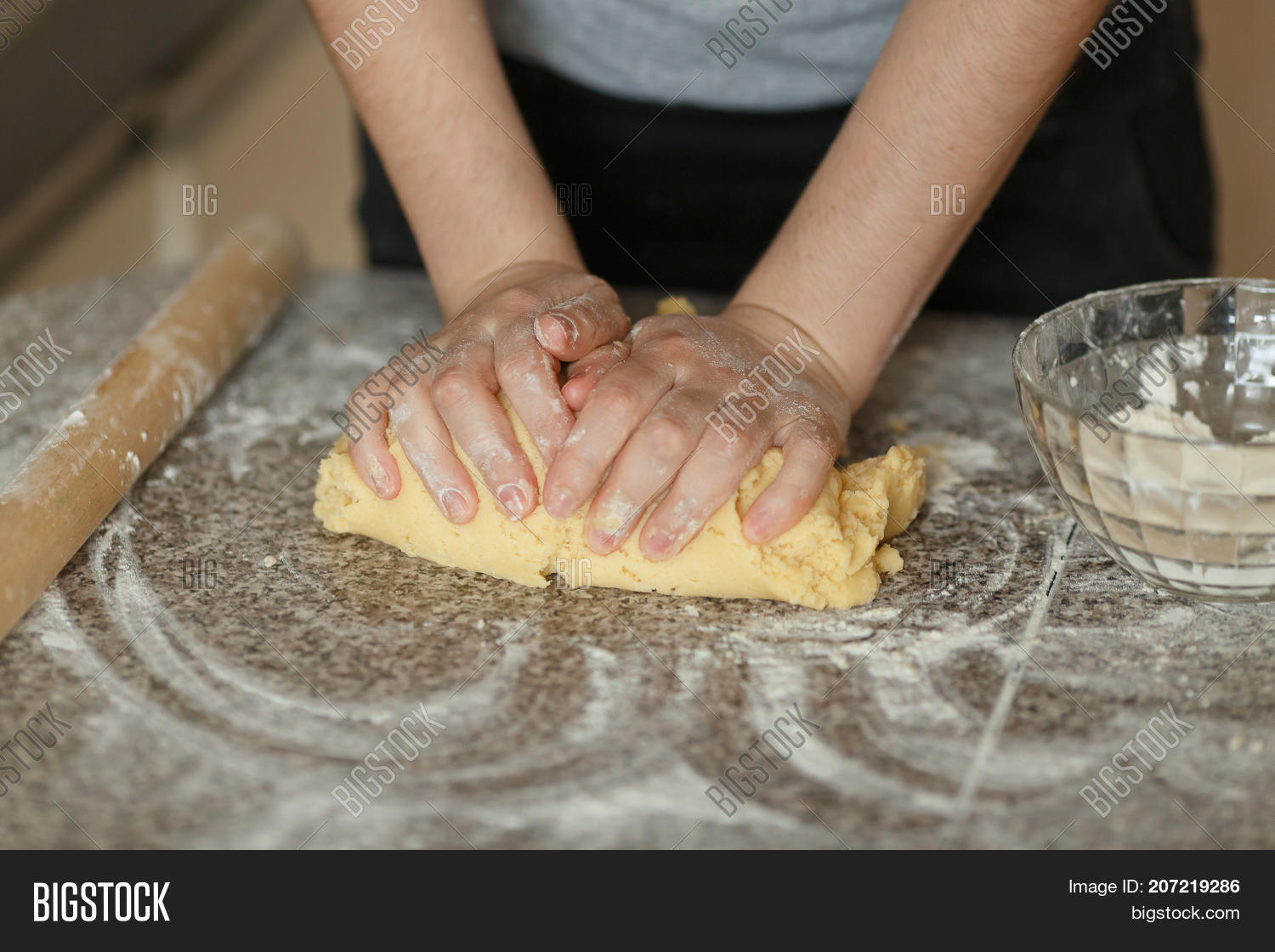 baker hands kneading dough in flour on table.