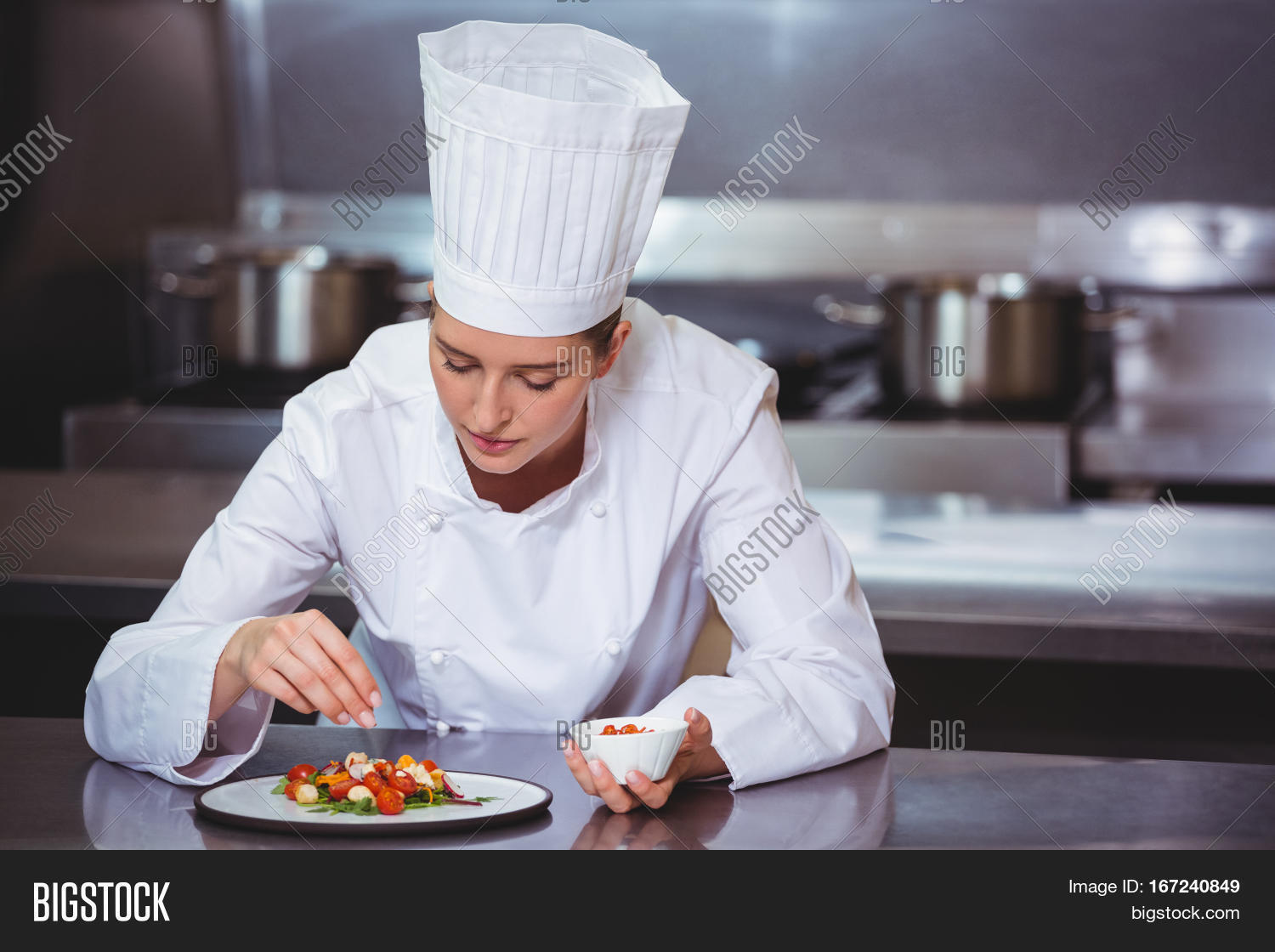 chef sprinkling spices on dish in commercial kitchen
