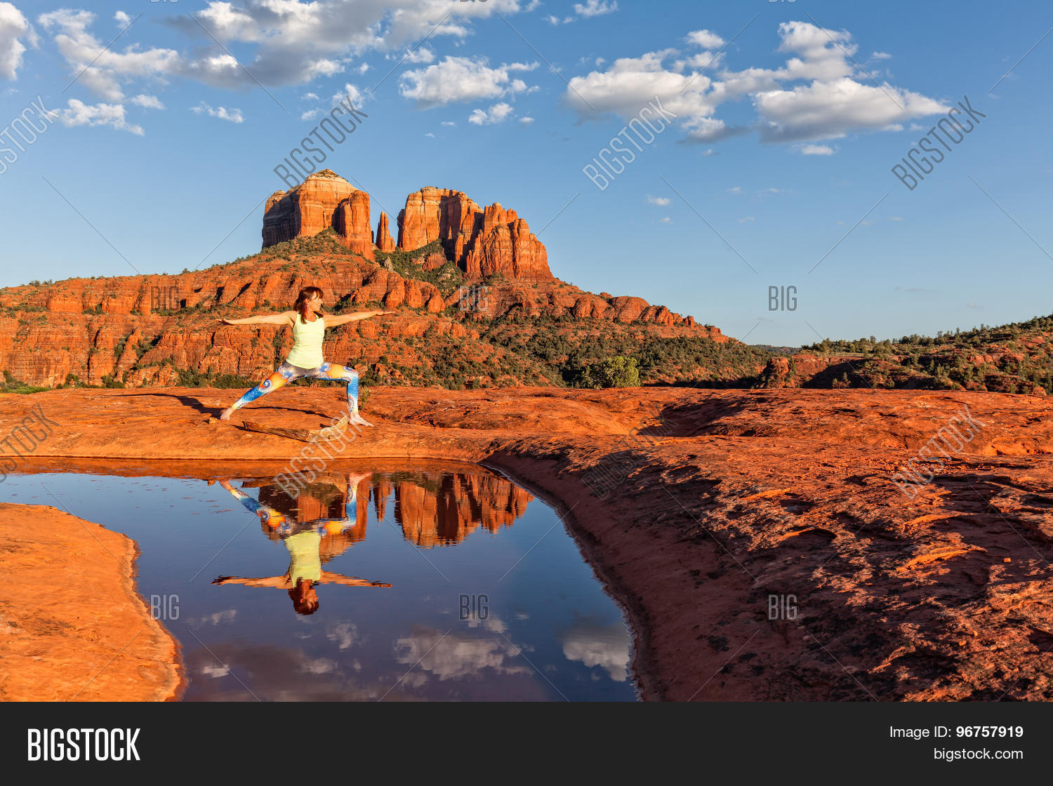 a woman practicing yoga reflected in a pond in front of