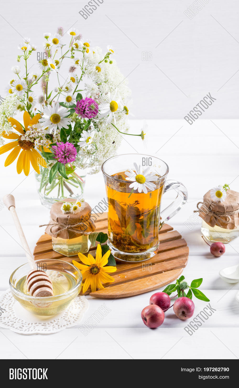 herbal tea with herbs and flowers in a glass tea pot with honey.