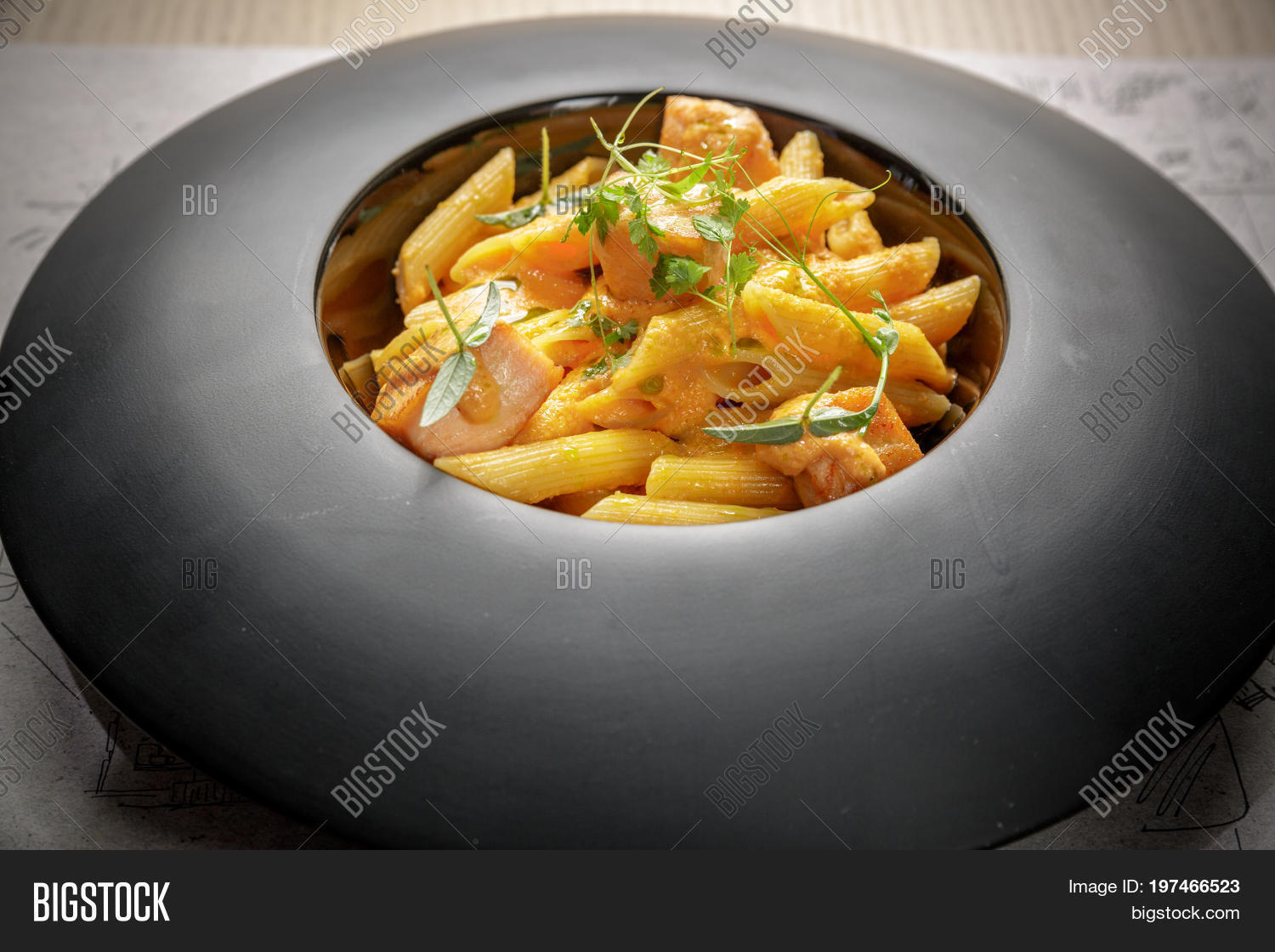 penne pasta with salmon and cheese cream on a black plate.