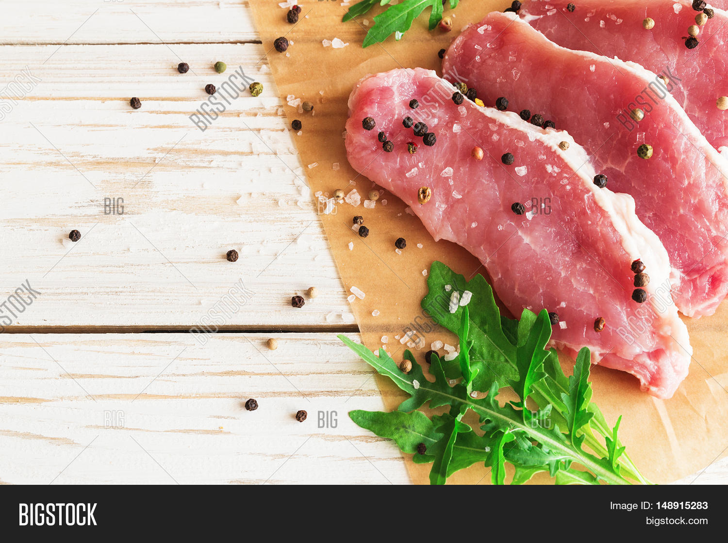 fresh raw pork meat with salt pepper and arugula.