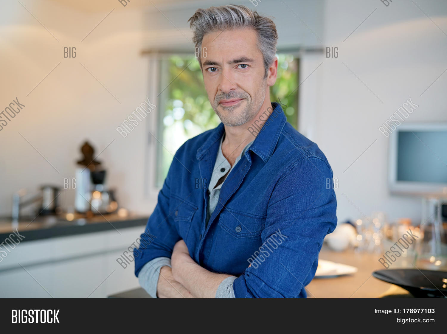 smiling handsome 45-year-old man standing by home kitchen