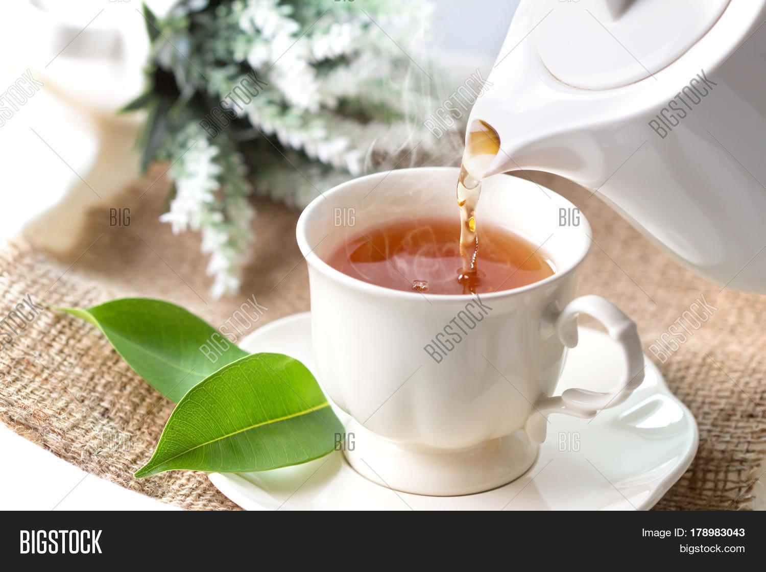close up pouring hot black tea in a white tea cup tea ceremony