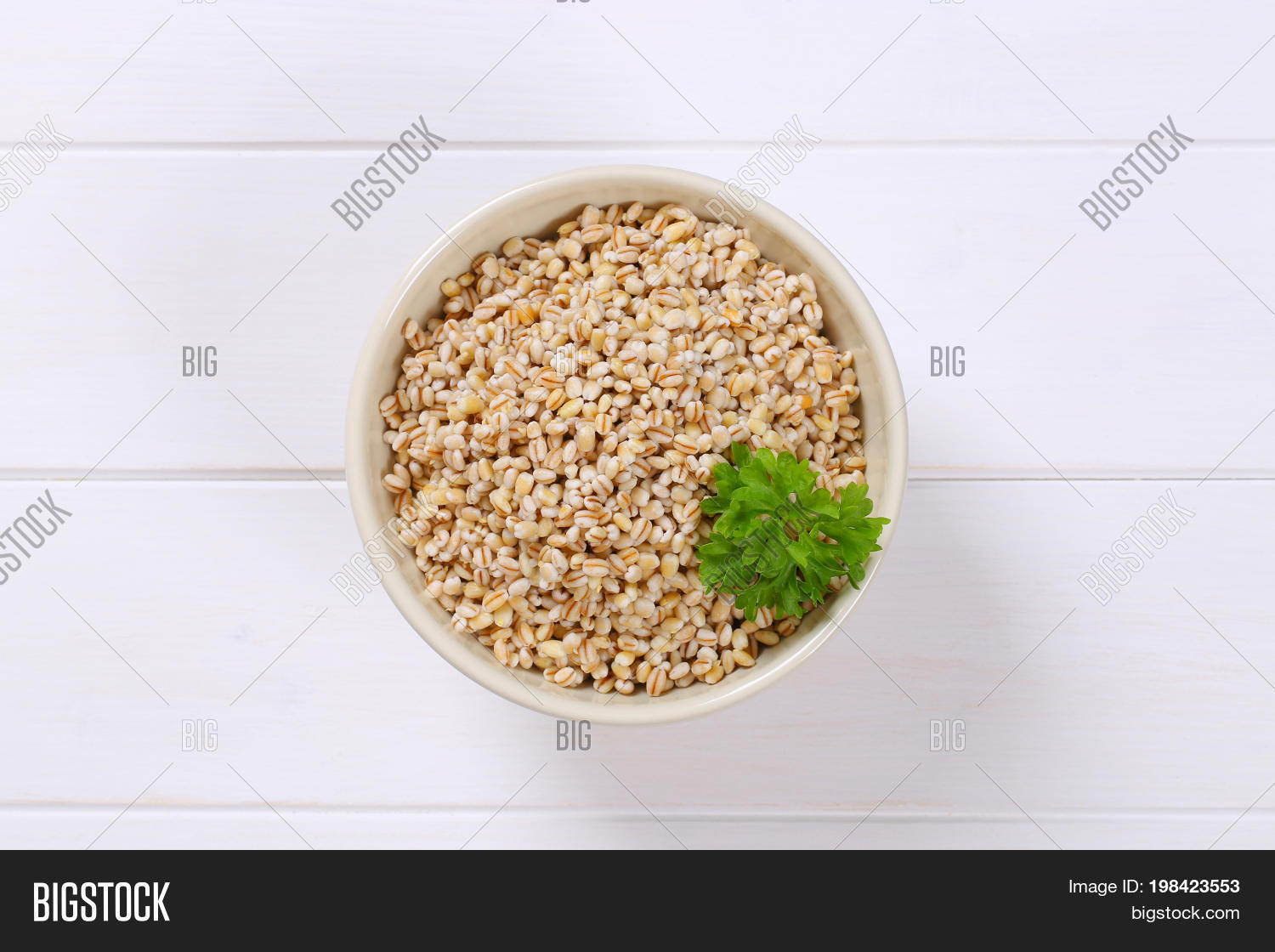 bowl of cooked pearl barley on white wooden background