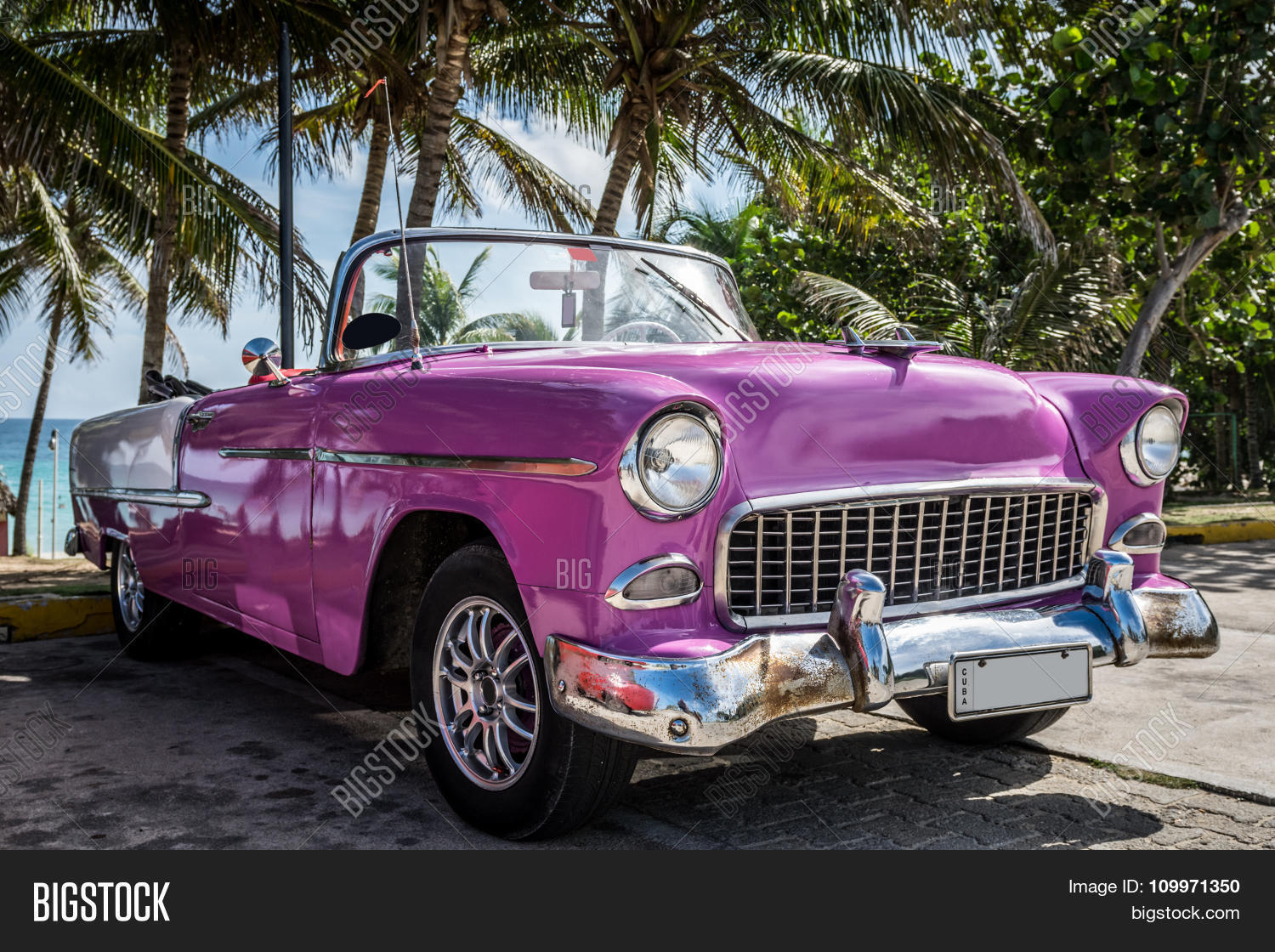 pink classic car parked near the beach in cuba