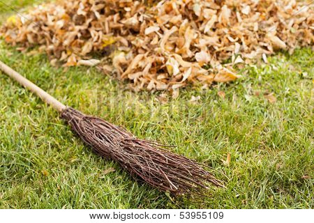fall clearing in garden - besom and a pile of leaves