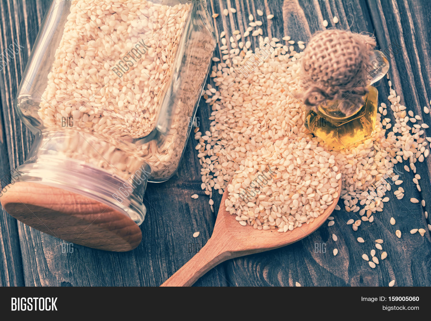 sesame oil in bottle sesame seeds in jar spoon on wooden back
