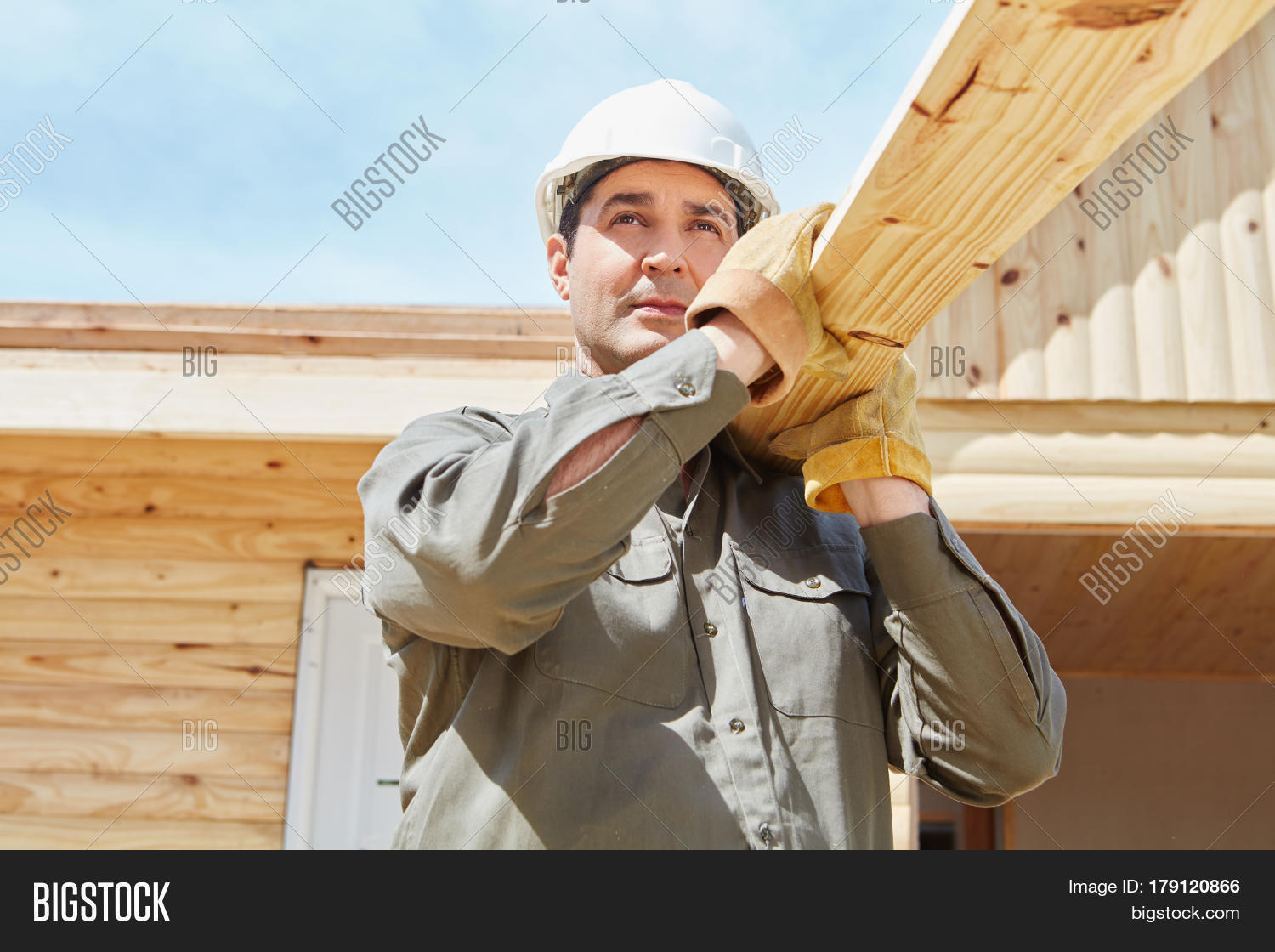 blue collar worker carrying wood in construction site
