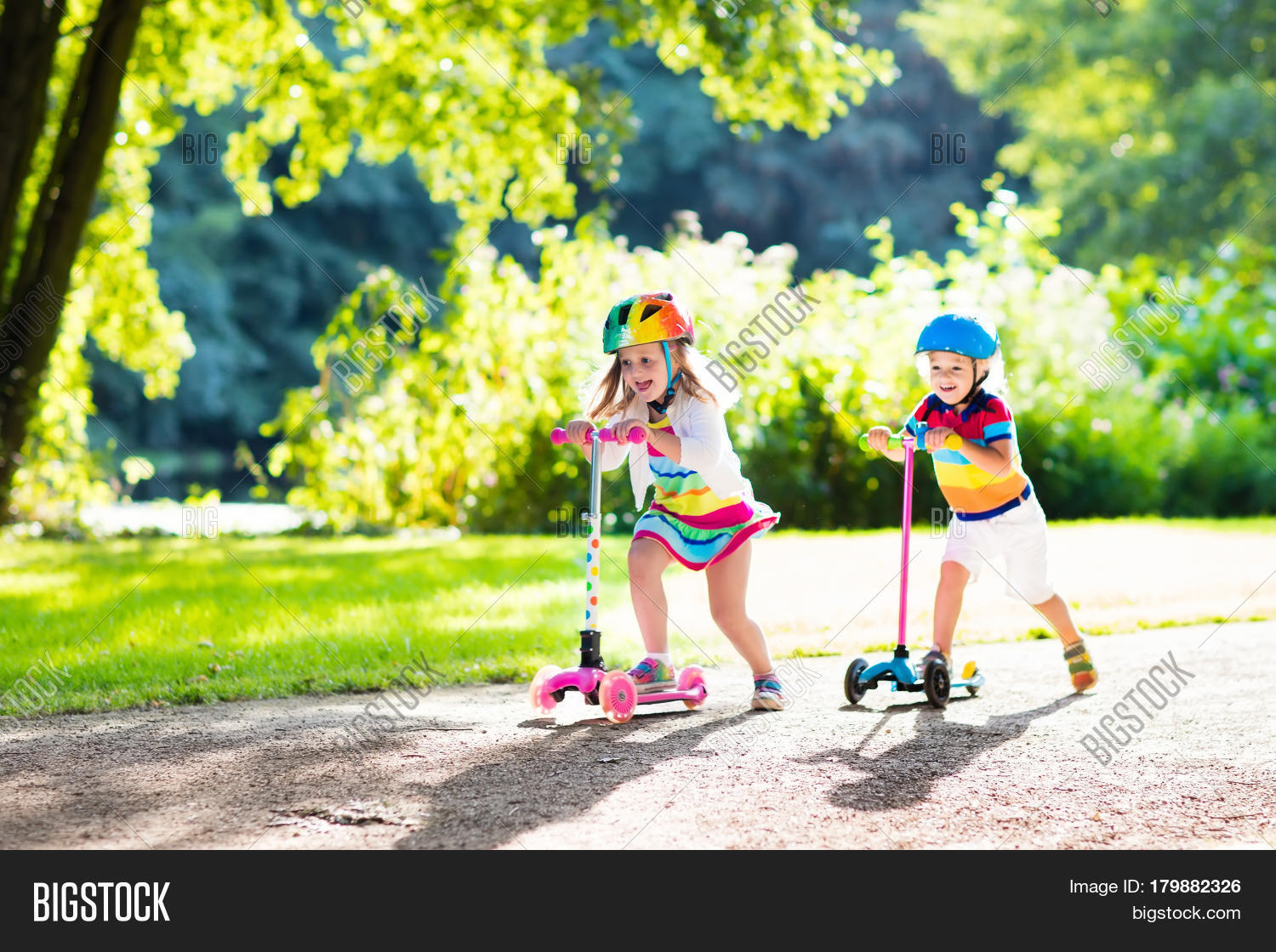 kids riding scooter in summer park.