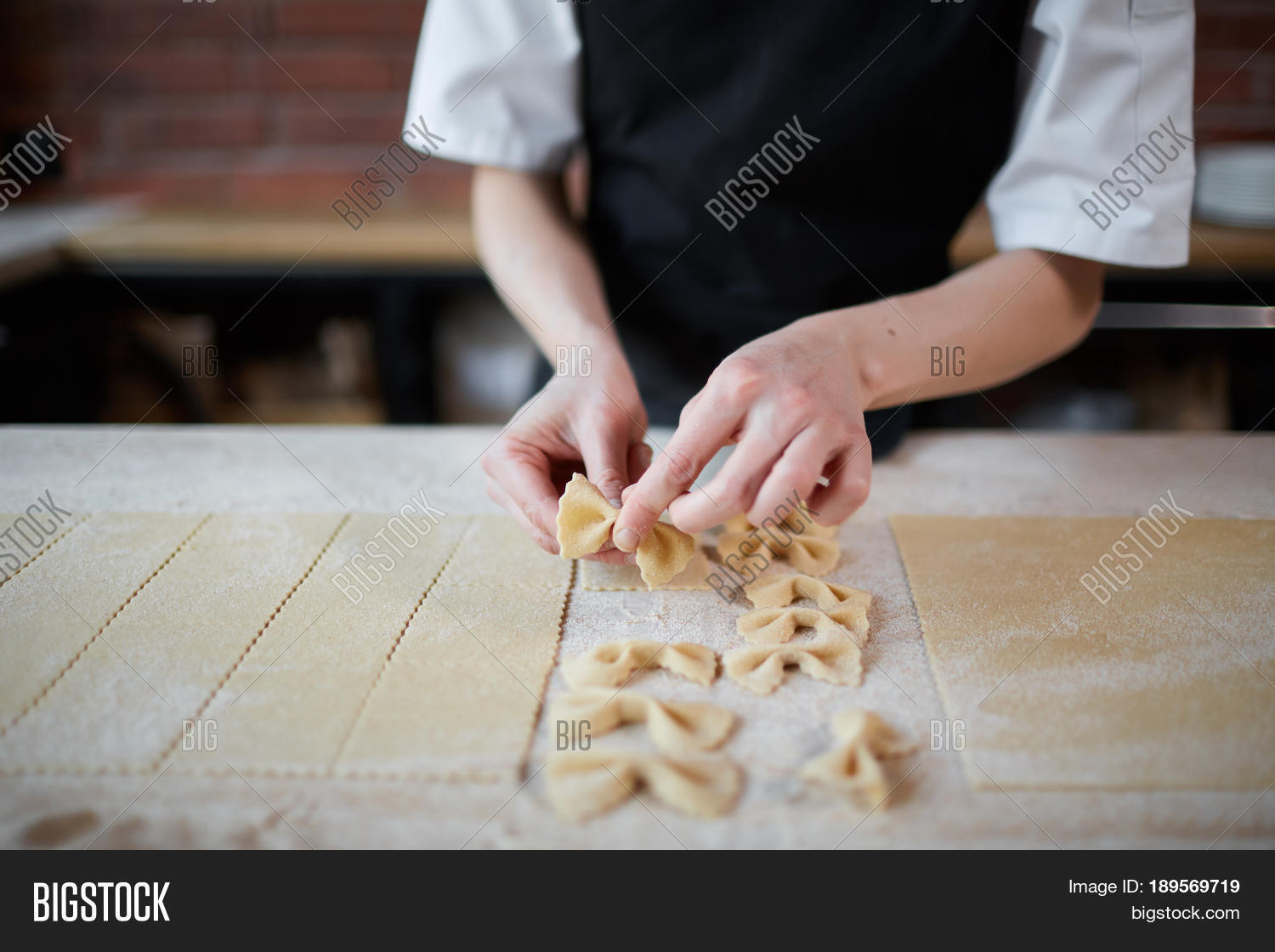 unrecognizable cook making farfalle pasta with dough in