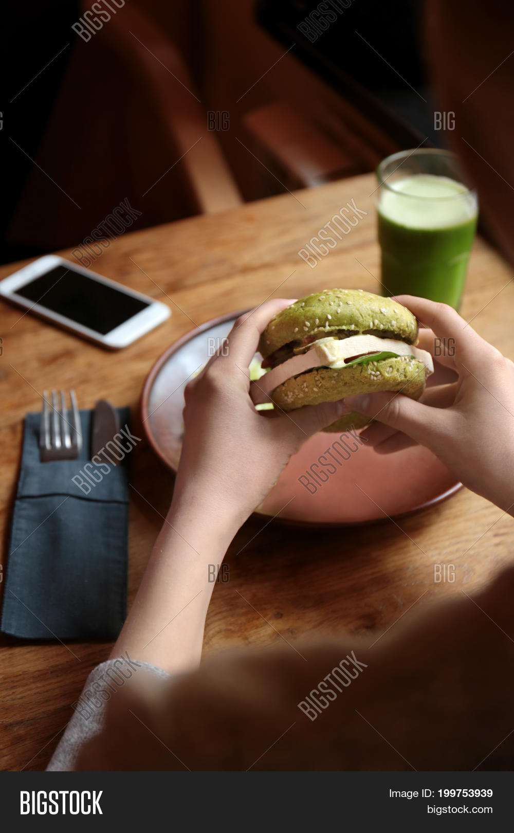 woman eating tasty green sandwich over table