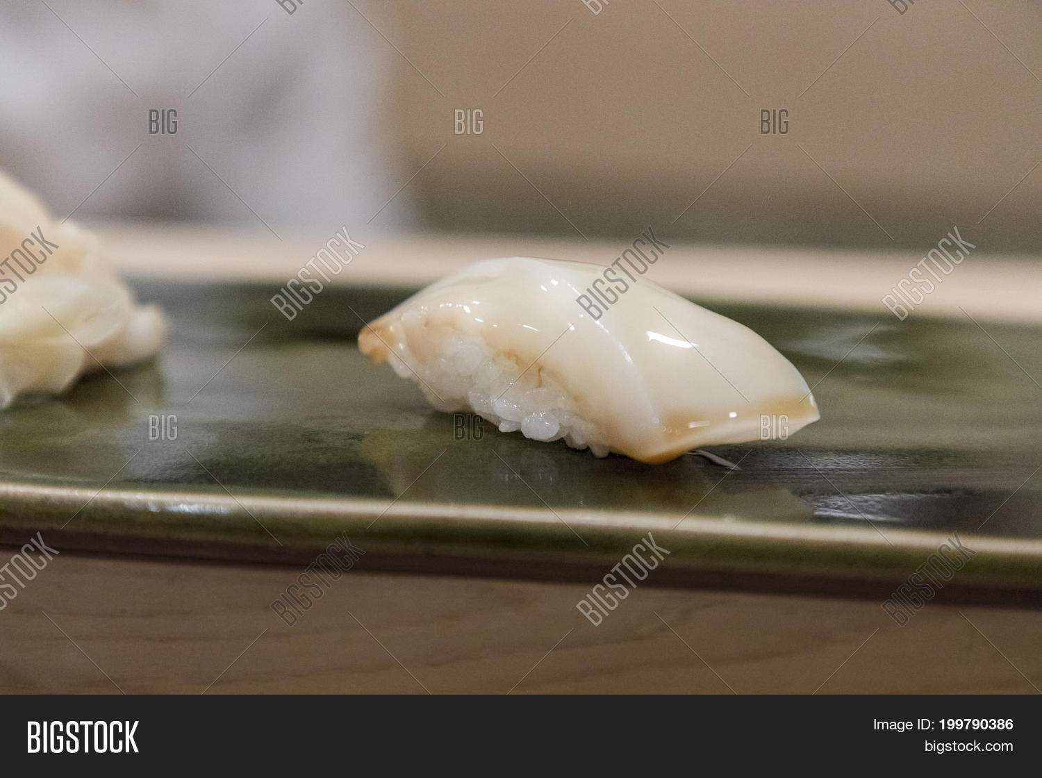 nigiri sushi with squid slice on white rice on green plate close